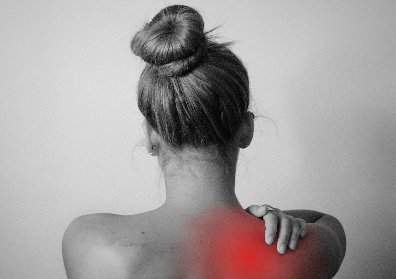 A person holding their neck/trapezius muscles, which are red indicating that they’re inflamed