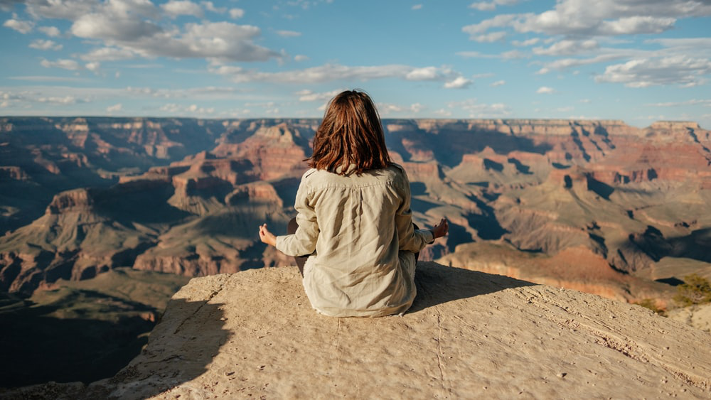 Girl meditating after using CBD on a mountain top.