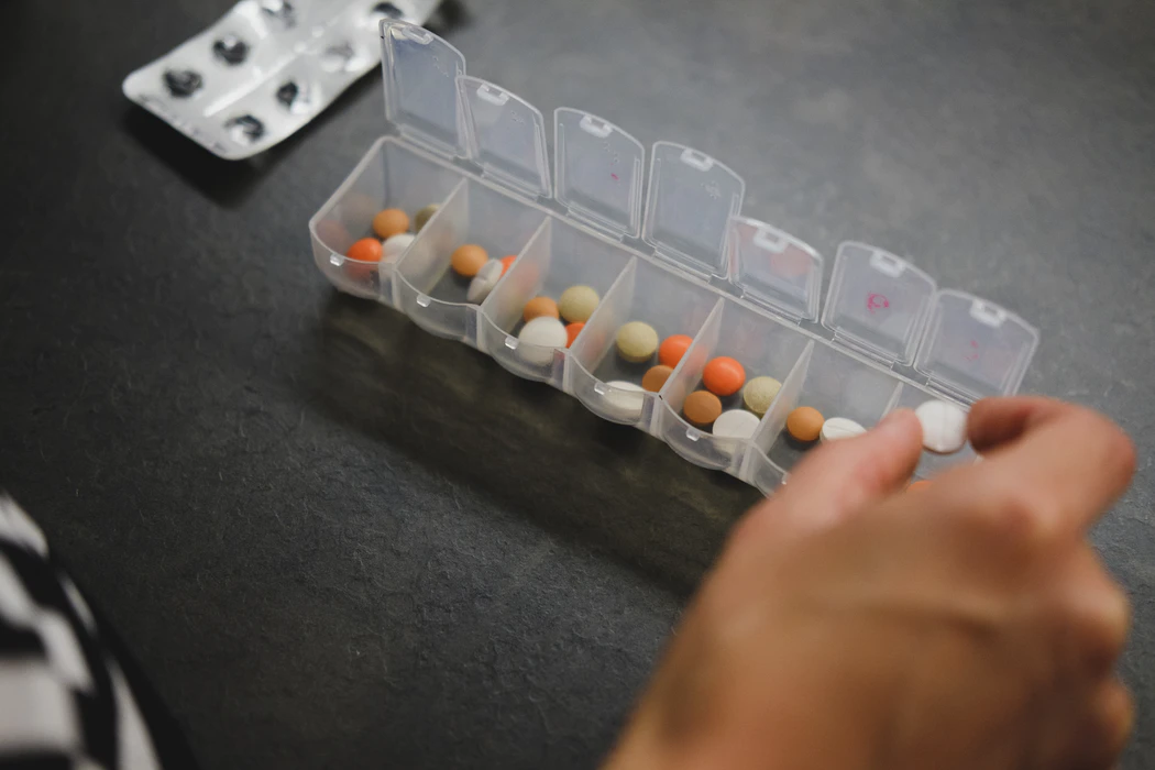 Overmedicated person taking a pill from their medicine box