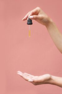 A woman holding a dropper of CBD oil and pouring onto her other hand