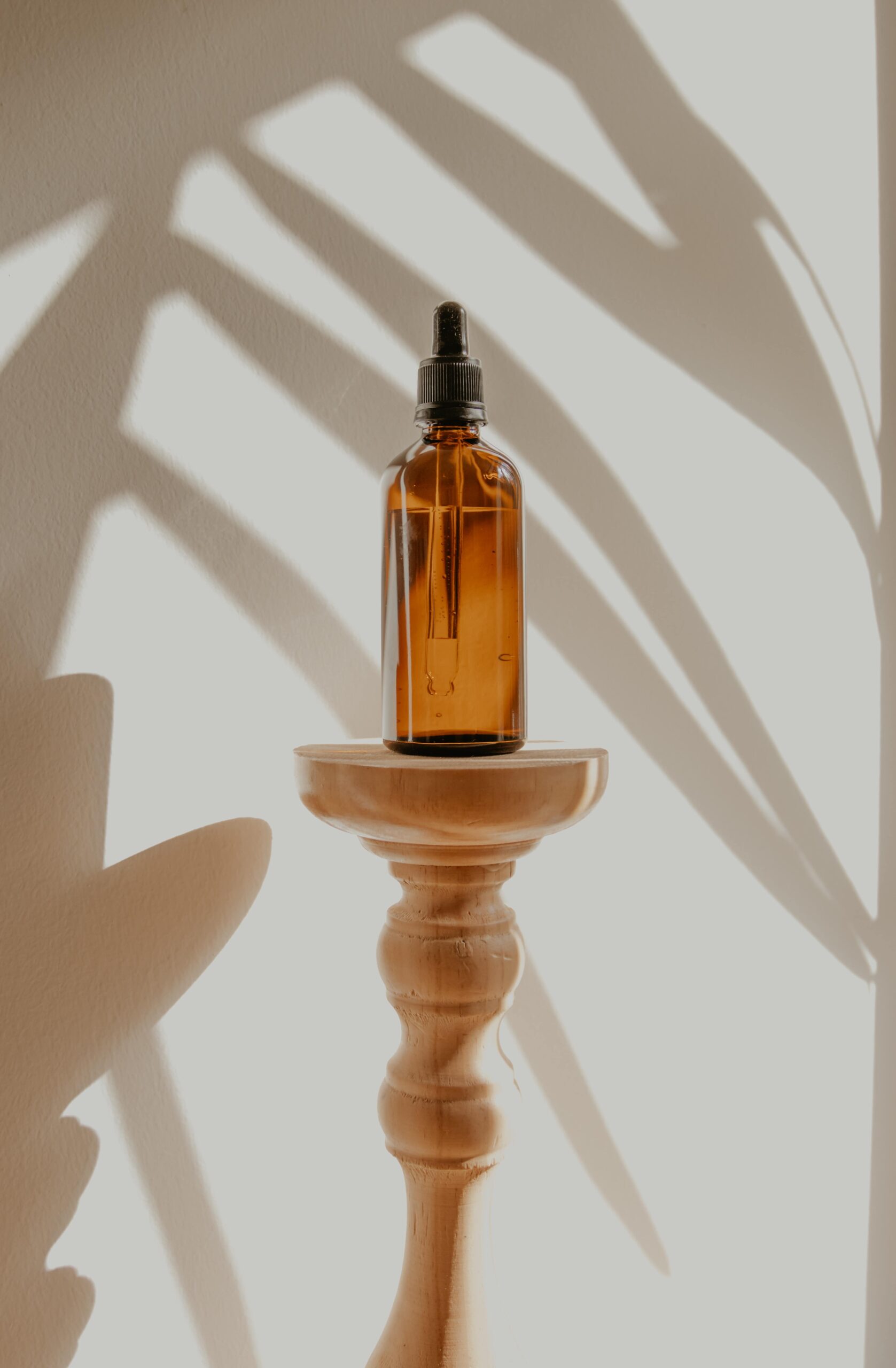 A CBD oil bottle is displayed on a table with a plant silhouette against the wall