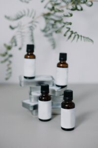 Four bottles of CBD oil are displayed on a white background with a blurred plant behind 